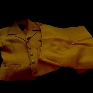 Gold suit jacket has gold button and skirt above knee